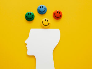 Contorno de uma cabeça com emojis coloridos em cima representando a inteligência emocional.