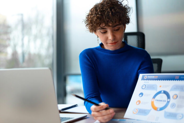 Mulher apontando para uma tela de notebook. Na tela, um esquema em círculo representando a avaliação do ciclo de gestão de desempenho.