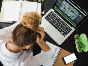 mulher com as mãos na cabeça com a saúde mental no trabalho abalada em frente ao computador.