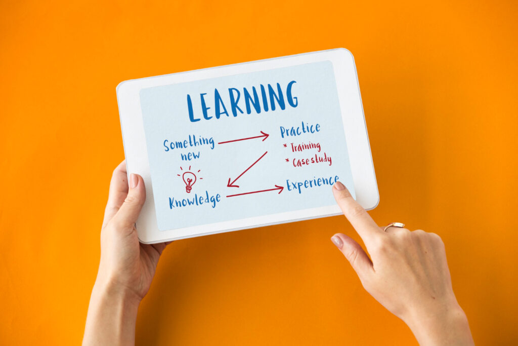 Mãos segurando um tablet com um esquema sobre metodologias de aprendizagem, destacando etapas como aprender algo novo, praticar, adquirir conhecimento e ganhar experiência.
