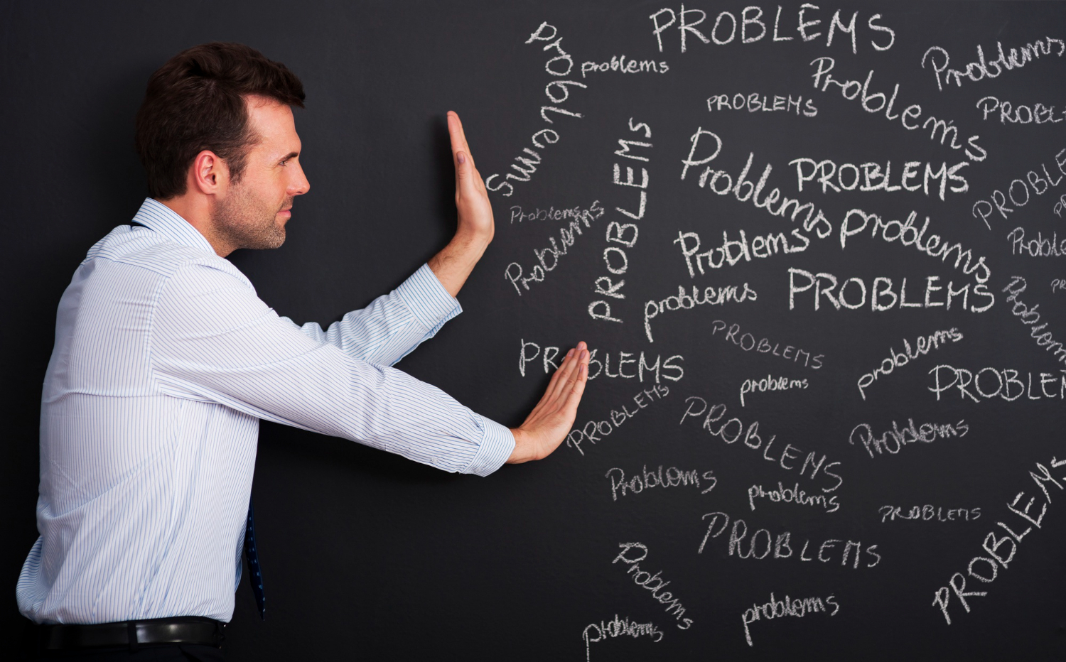 Profissional diante de uma parede repleta de problemas, representando o desafio de encontrar soluções e aplicar a resolução de problemas no ambiente de trabalho.